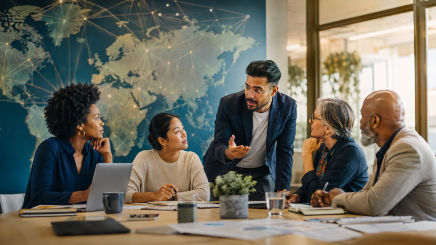 Image of four people sitting around a desk listening to one person speak